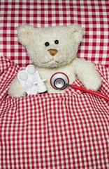 Patient: Kranker Teddyb&auml;r liegt mit Grippe im Bett
