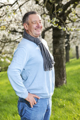 Naklejka na ściany i meble Friendly man in nature under blooming cherry tree