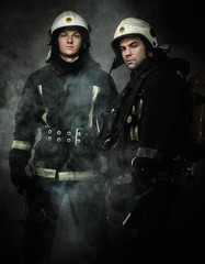 Two firefighters with axes in a smoke