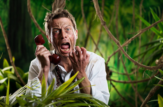 Furious businessman on the phone lost in jungle