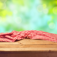 Empty wooden deck table with tablecloth over nature background