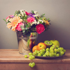 Flower bouquet and fresh fruits on wooden table