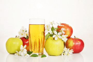 Glass of fresh apple juice with ripe apples and white flowers