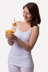 Smiling young woman looks at a glass of orange juice.