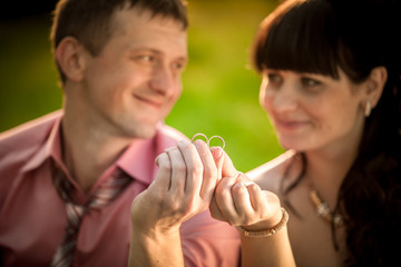 portrait with selective focus on wedding rings held by smiling c