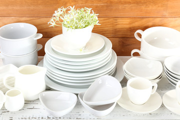 Different tableware on shelf, on wooden background