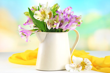 Bouquet of freesias in pitcher on table on natural background