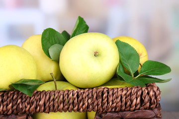 Ripe sweet apples with leaves in wicker crate