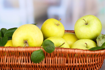 Ripe sweet apples with leaves in wicker basket