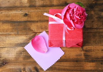 Pink gift with bow and flower on wooden table close-up