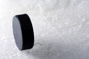 Black hockey puck on ice rink background