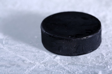 Black hockey puck on ice rink background