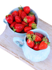 Ripe sweet strawberries in color mugs