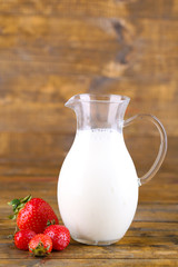 Ripe sweet strawberries and jug with milk