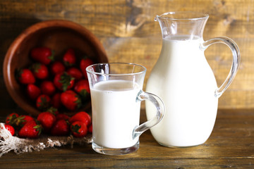 Ripe sweet strawberries in wooden bowl and jug with milk