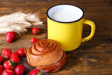 Ripe sweet strawberries in wooden bowl and jug with milk