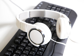Fototapeta na wymiar Headphone and keyboard close-up on white desk background