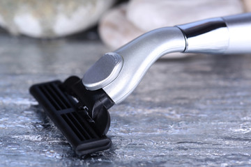 Obraz premium Shaving razor on stones on bright background
