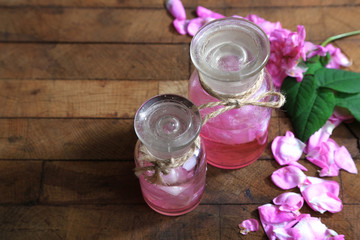 Rose oil in bottles on color wooden background