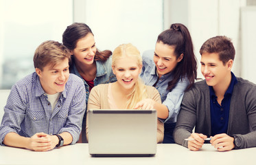 smiling students looking at laptop at school