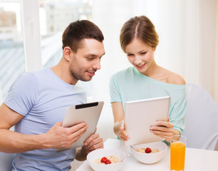 smiling couple with tablet pc reading news