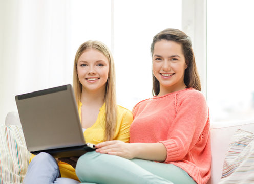 two smiling teenage girls with laptop at home