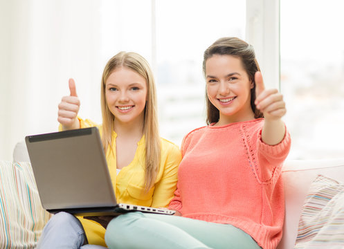 two smiling teenage girls with laptop at home