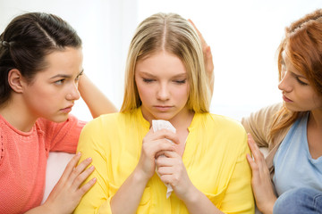 two teenage girls comforting another after breakup