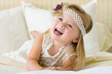 Little girl laughing on bed