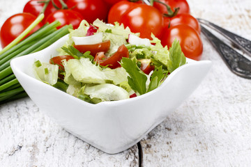 Bowl of fresh salad on wooden table