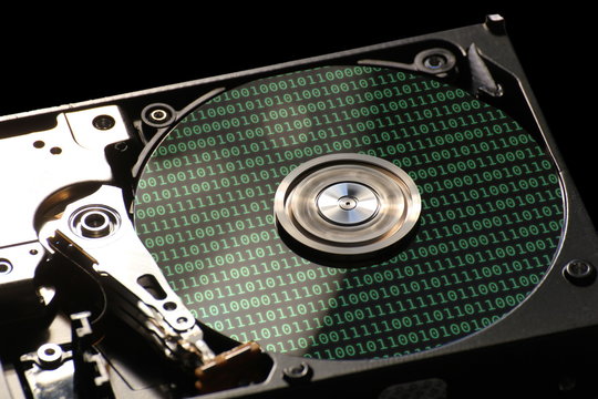 ard disk on a black background with reflections of binary code