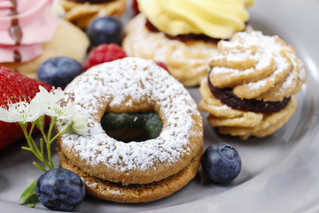 Assorted cookies and fruits on grey ceramic plate