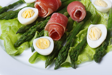 Boiled quail eggs with ham and asparagus close-up top view