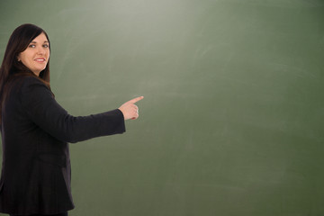 Lehrerin zeigt auf eine leere Schultafel