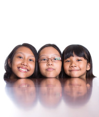 Teenage sisters with face reflection on wooden table surface