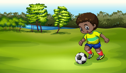 A young boy playing soccer near the river