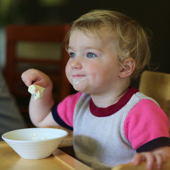 Adorable toddler girl eating ice cream in cafe