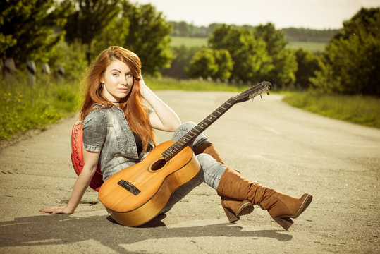 woman with guitar at asphalt road
