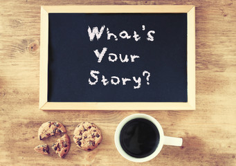 blackboard with the phrase whats your storry and cup of coffee a