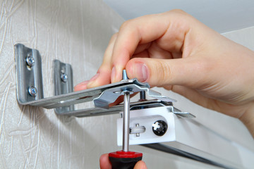 vertical blinds mounting brackets, hand with a screw close up