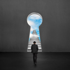 Obraz premium Businessman walking toward key shape door with stairs outside