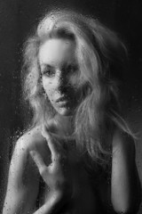 Portrait of naked girl behind the wet glass