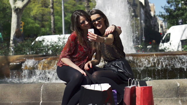 Women taking selfie and sitting on fountain, slow motion shot at