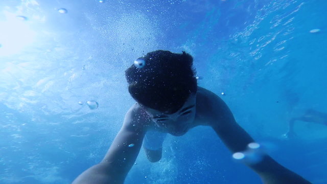 Happy active teenage in the swimming pool, underwater view