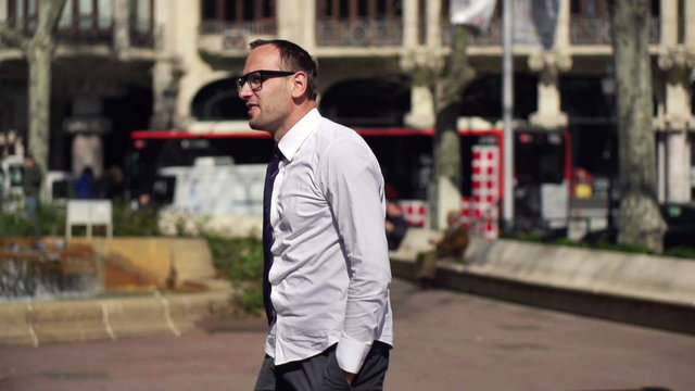 businessman holding his jakcet and walking along the street on a