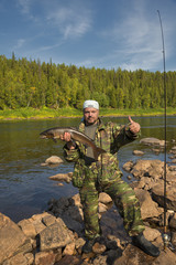 Naklejka premium Fisherman holding a large fish salmon.