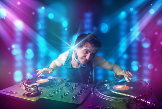 Dj mixing music in a club with blue and purple lights
