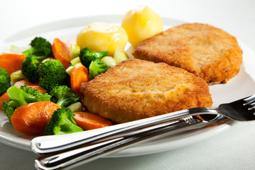 Fried pork chop with boiled potatoes and vegetables