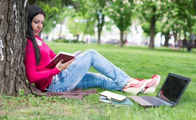 beautiful girl reads book in a park