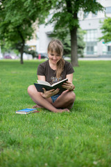 beautiful girl reads book in a park